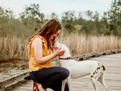 Me wearing a yellow blouse and blue jeans, and Penny, photographed on a wooden bridge spanning a wetland